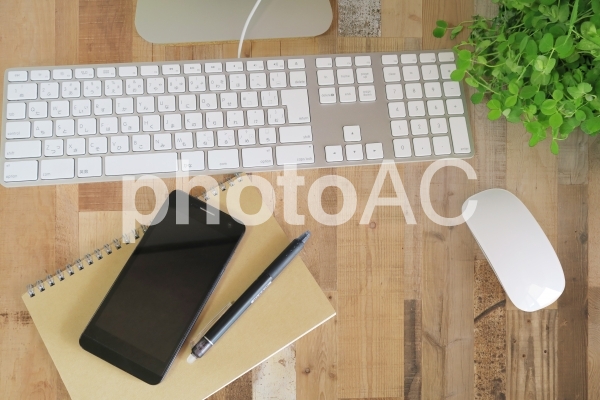 パソコンとスマートフォンの仕事場-茶色の木目デスク パソコンとスマートフォンの仕事場-茶色の木目デスクの写真