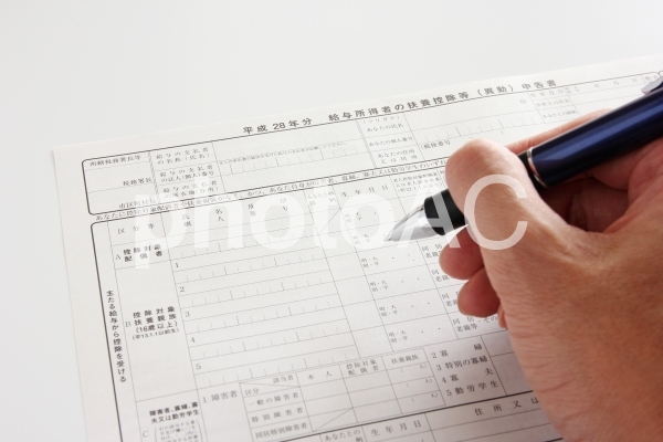 申告書とペンを持った手 申告書とペンを持った手の写真