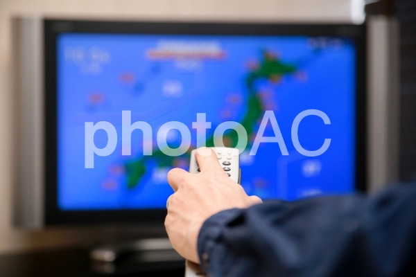 天気予報をテレビで見る男性 天気予報をテレビで見る男性の写真