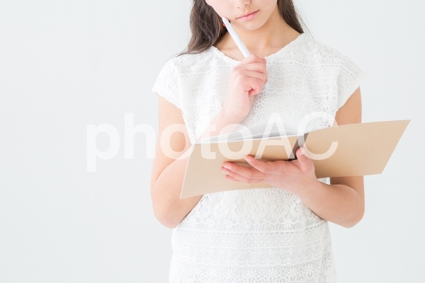 ノートを見て考える女の子 ノートを見て考える女の子の写真