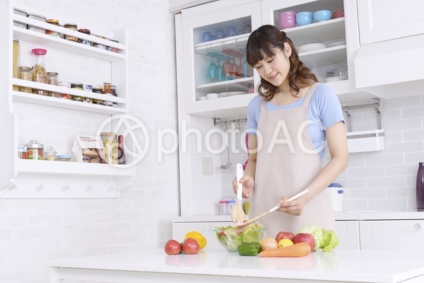 キッチンでサラダを混ぜる女性3 キッチンでサラダを混ぜる女性3の写真