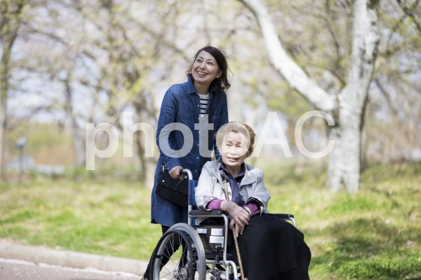 散歩をする車椅子の高齢女性 散歩をする車椅子の高齢女性の写真