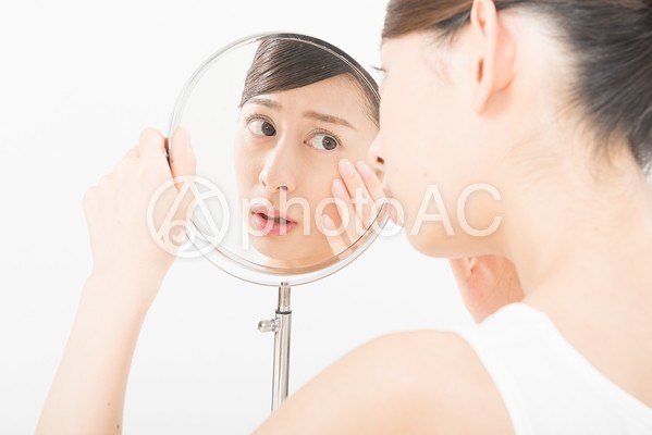 鏡で肌をチェックする女性(鏡越し)7 鏡で肌をチェックする女性(鏡越し)7の写真