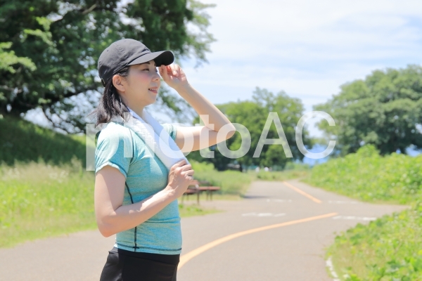 熱中症・日焼け対策にキャップを被るランナーの女性 熱中症・日焼け対策にキャップを被るランナーの女性の写真