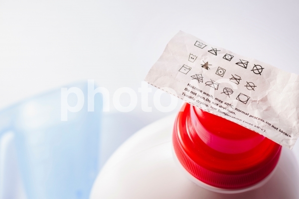 洗剤の計量カップと液体洗剤と洗濯表示タグ 洗剤の計量カップと液体洗剤と洗濯表示タグの写真