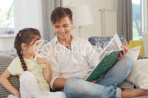 ソファで娘と絵本を読む父親4 ソファで娘と絵本を読む父親4の写真