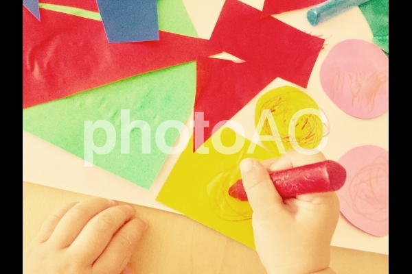 折り紙のはり絵とクレヨンで遊ぶこどもの手 折り紙のはり絵とクレヨンで遊ぶこどもの手の写真