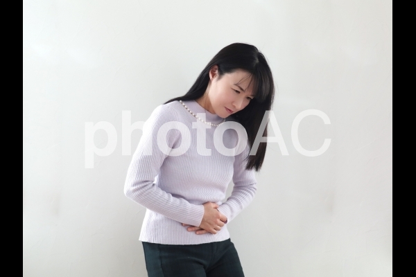 お腹を抑える女性 お腹を抑える女性の写真