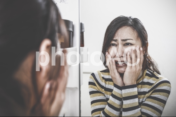 鏡をみて驚く女性 鏡をみて驚く女性の写真