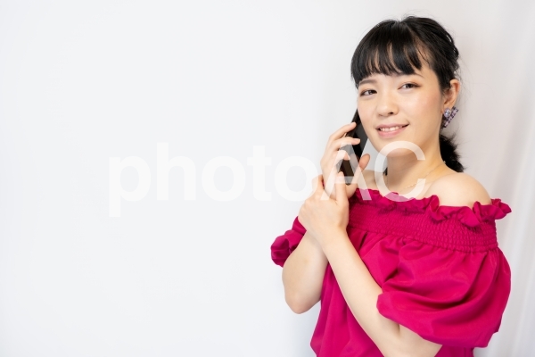 スマホで通話する女性(白背景) スマホで通話する女性(白背景)の写真