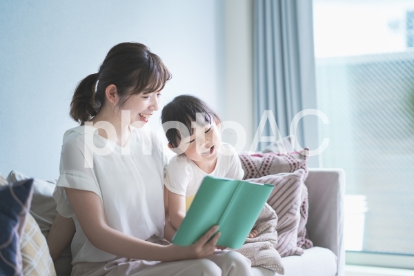 ソファに座って絵本を読む親子 ソファに座って絵本を読む親子の写真