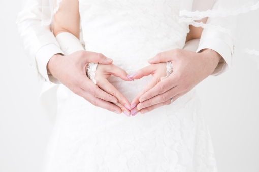 手をハートにする新郎新婦 妊活は二人協力して