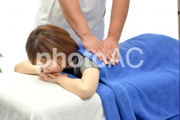 うつ伏せの女性患者に施術する整体師23 うつ伏せの女性患者に施術する整体師23の写真