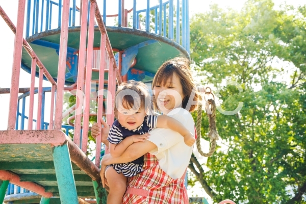 やんちゃな子供を守るエプロン姿の女性 やんちゃな子供を守るエプロン姿の女性の写真