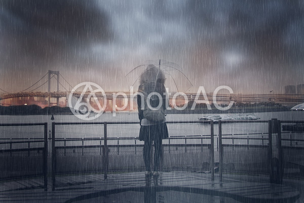 雨の中海の前に佇む女性 雨の中海の前に佇む女性の写真