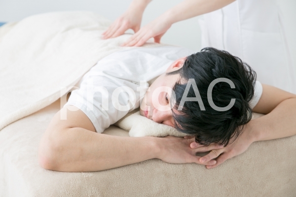 腰のマッサージをうける男性 腰のマッサージをうける男性の写真