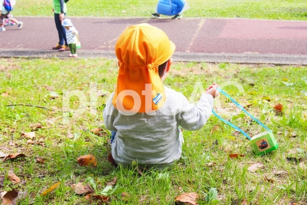 芝生の斜面に座る子供 芝生の斜面に座る子供の写真