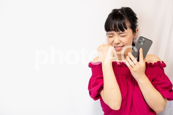 スマホを持ってガッツポーズをする女性(白背景) スマホを持ってガッツポーズをする女性(白背景)の写真
