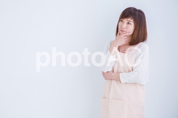 考えるエプロン姿の女性 考えるエプロン姿の女性の写真
