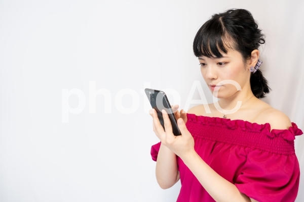 スマホを操作する女性(白背景) スマホを操作する女性(白背景)の写真