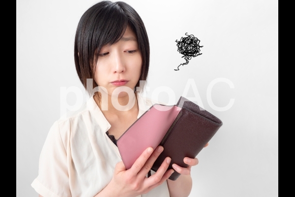 財布の中身を見てガッカリする女性のイメージ 財布の中身を見てガッカリする女性のイメージの写真