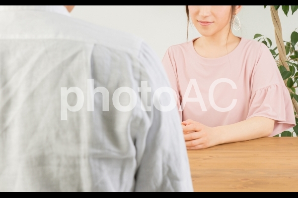 テーブルで話す男女 テーブルで話す男女の写真