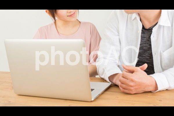 笑顔でノートパソコンを操作する男女 笑顔でノートパソコンを操作する男女の写真