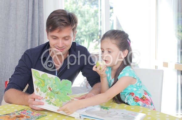 女の子に絵本を読み聞かせる男性2 女の子に絵本を読み聞かせる男性2の写真