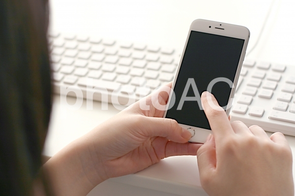 スマホをする女性の後姿 スマホをする女性の後姿の写真