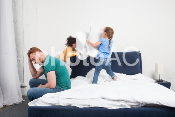 ベッドで暴れる子どもと疲れたお父さん2 ベッドで暴れる子どもと疲れたお父さん2の写真