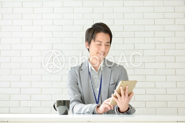 タブレットを操作している男性 タブレットを操作している男性の写真
