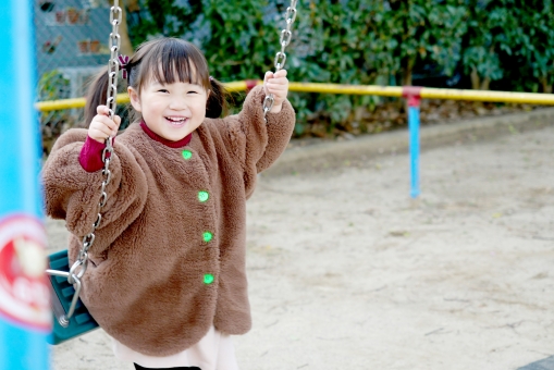 公園のブランコで遊ぶ子供の写真