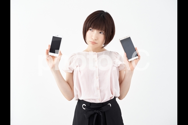 キャリアと格安SIMスマホを比較する女性 キャリアと格安SIMスマホを比較する女性の写真