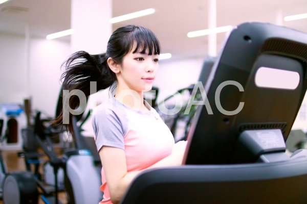 ランニングマシンで走る女性 ランニングマシンで走る女性の写真