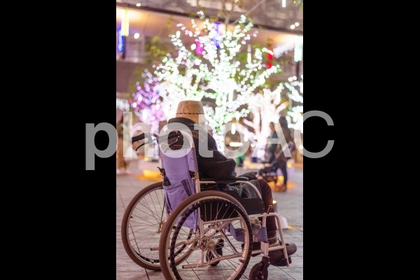 車椅子に乗ってイルミネーションを見ているシニア女性 車椅子に乗ってイルミネーションを見ているシニア女性の写真