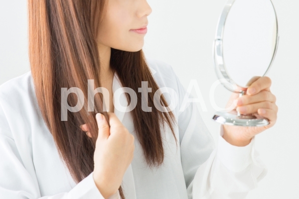 鏡で髪をチェックする女性 鏡で髪をチェックする女性の写真