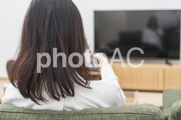 ソファーに座ってテレビを見る女性 ソファーに座ってテレビを見る女性の写真